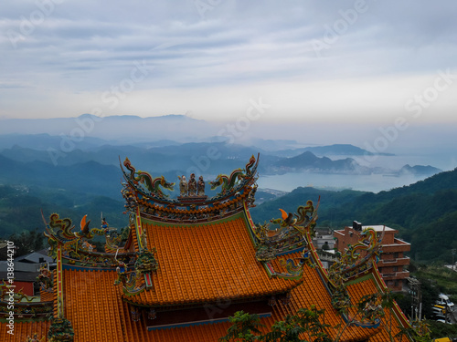 Traditional Chinese style roof in yellow with misty landscape seaview © TChareon