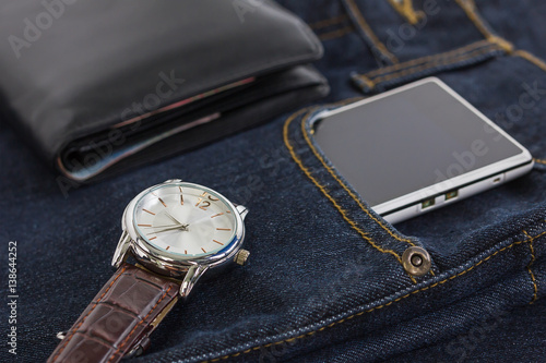 Wrist watch and smartphone on denim jeans