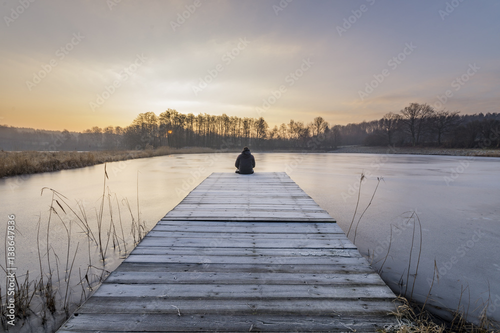 Obraz premium silhouette sitting on the bridge over the frozen lake