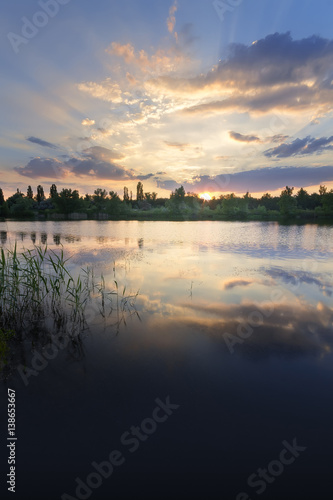 the sunset on the lake on a summer's evening / bright summer photo of the sun's rays Ukraine