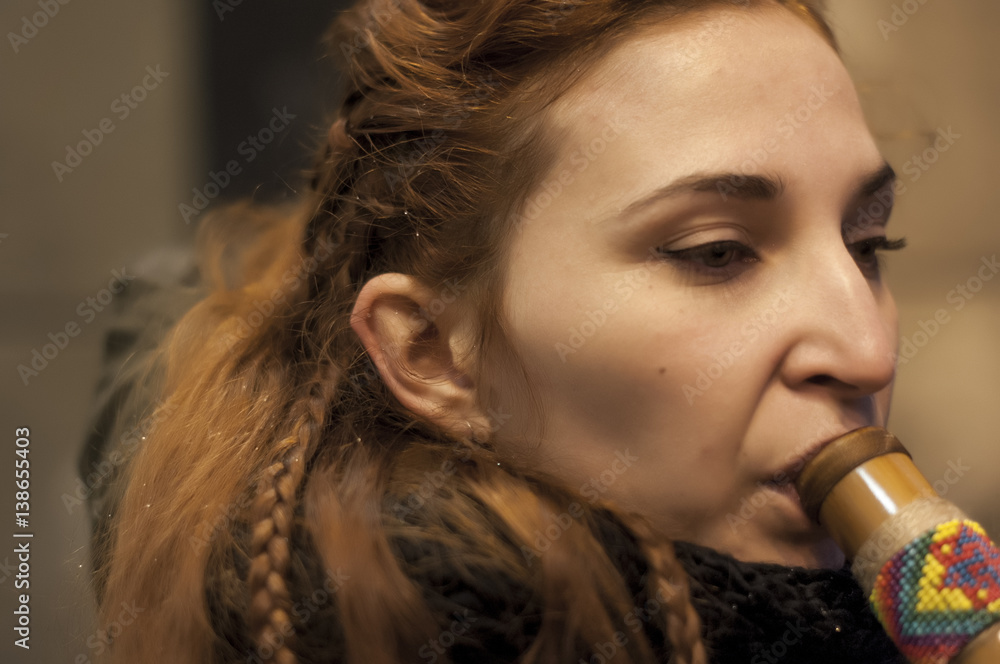 Obraz premium portrait close up of a woman playing the flute thick hair with braids