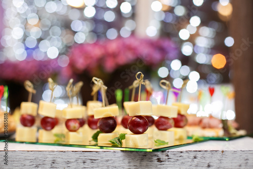 Appetizer of grape, pineapple cubes and cheese are on wooden skewers.