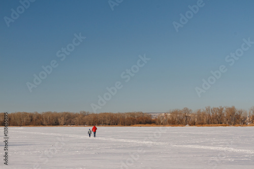 The father and his son walk on a frozen river