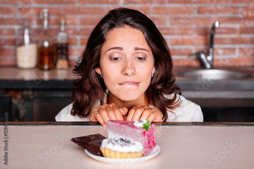 Woman on the diet craving to eat cake Fototapeta