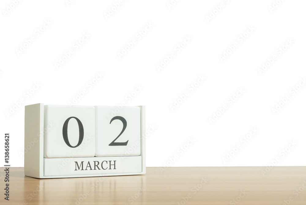 Closeup surface white wooden calendar with black 2 march word on blurred brown wood desk isolated on white background with copy space , selective focus at the calendar Closeup surface white wooden calendar with black 2 march word on blurred brown wood desk isolated on white background with copy space , selective focus at the calendar