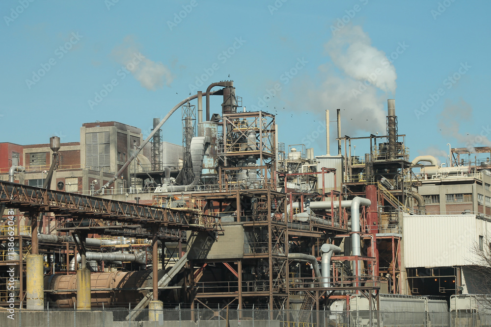 A large industrial building with smoke coming out of the stacks.