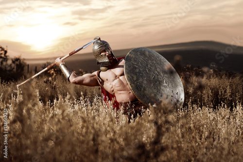 Photos Strong Spartan warrior in battle dress with a shield and a spear