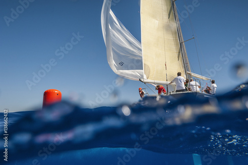 Sailing boat with spinnaker on windward mark - red buoy. Waterline view.  photo