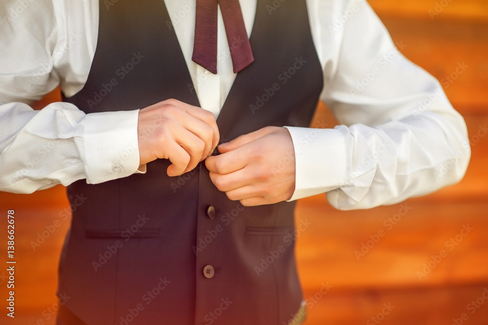 Fototapeta premium two hands close the first button of the vest