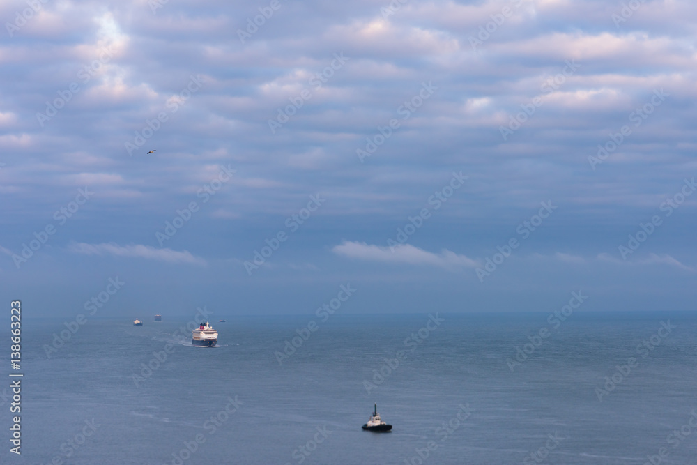 Fototapeta premium Large ocean cruise ship following small boat in ocean