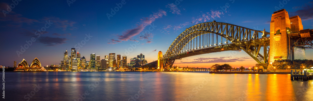 Naklejka premium Sydnej. Panoramiczny obraz Sydney w Australii z mostem Harbour Bridge podczas godziny zmierzchu niebieski.