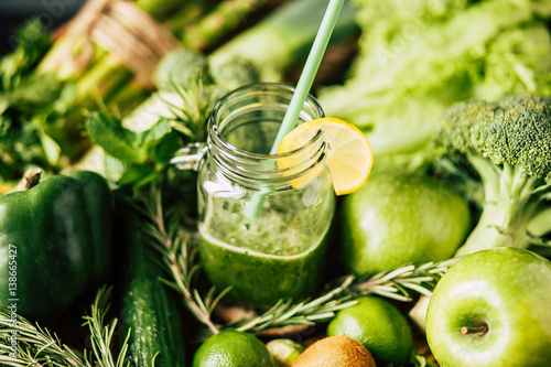 Freshly blended green fruit smoothie in glass jar with straw. photo