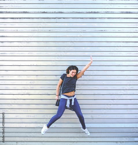 Girl jumps of joy against huge silver garage door background - Happiness concept