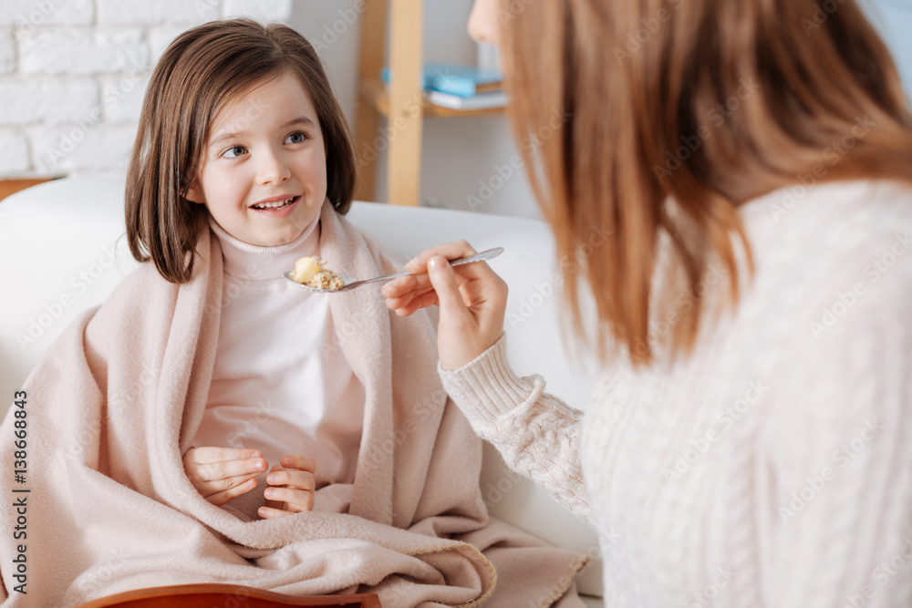 Positive cute girl eating breakfast with her mother Positive cute girl eating breakfast with her mother