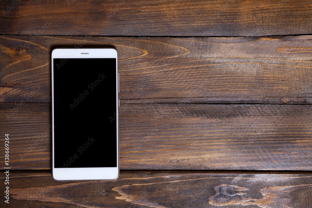 White mobile phone on a wooden background White mobile phone on a wooden background
