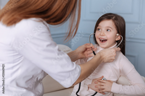 Positive cute little girl playing with stethoscope