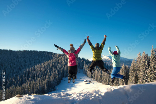Three young friends jumping and having fun on the snowy mountains