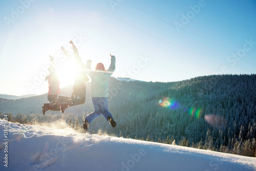 Three young friends jumping and having fun on the snowy mountains
