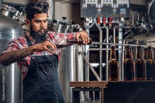 Indianr male manufacturer tasting and presenting craft beer in the microbrewery. photo