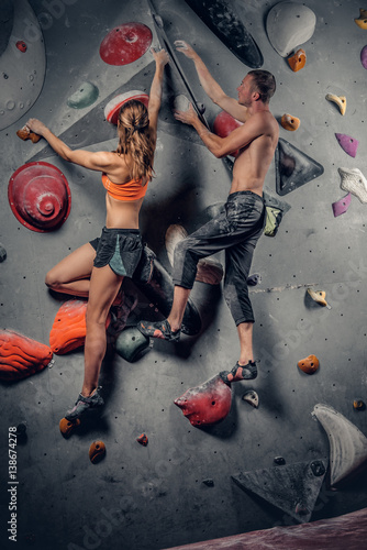 Male and female climbing on a climbing wall.