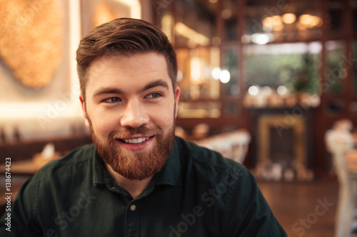 Handsome young bearded man sitting in cafe.