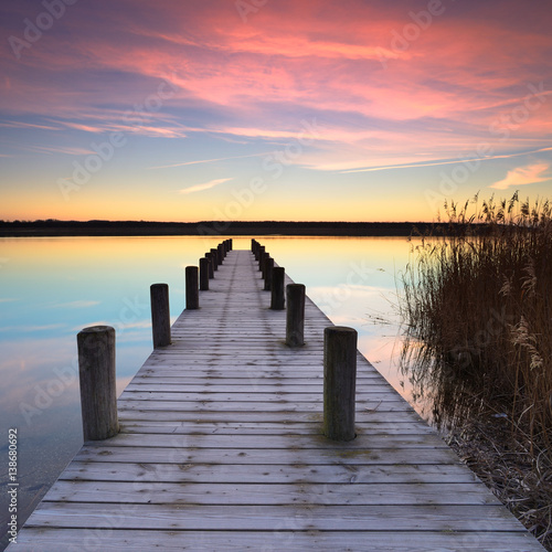 Fototapeta Ciche jezioro o wschodzie słońca, drewniane molo pokryte szronem