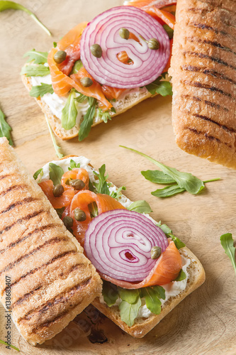 homemade baguette with smoked salmon, onions and arugula. Wooden