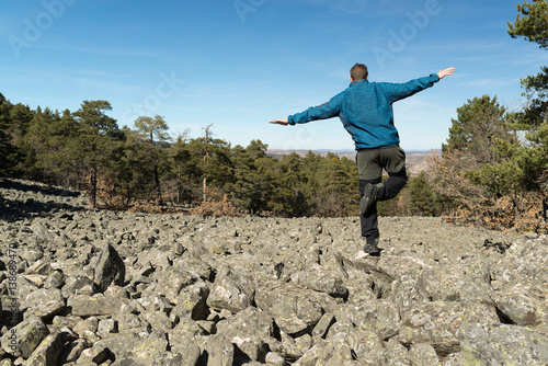 Hombre joven en equilibrio en un lecho rocoso de un antiguo glaciar llamado r  o de piedras