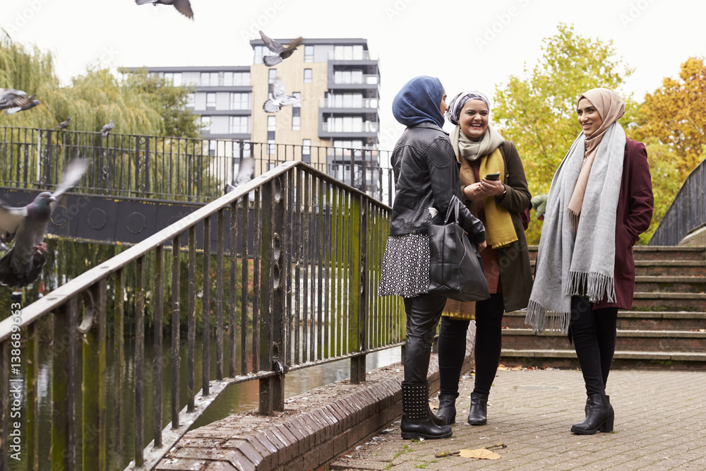 Muslim Female Friends Using Mobile Phone In Urban Setting