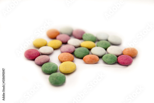 Colored candy. Multicolored colorful candy with white background closeup. Colorful chocolate button candies spread randomly on white background. Background image of sweet candies or chocolate buttons.