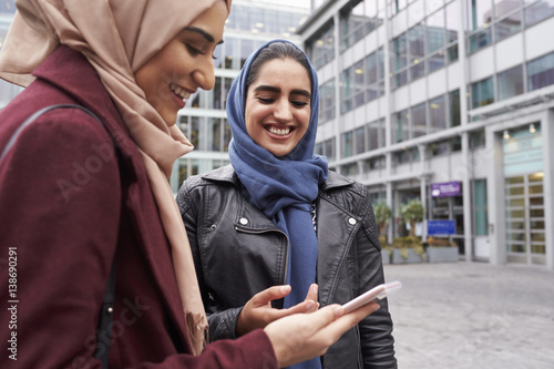 British Muslim Women Texting On Mobile Phone Outside Office
