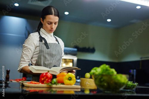 Young woman with cookery book preparing food at home © pressmaster
