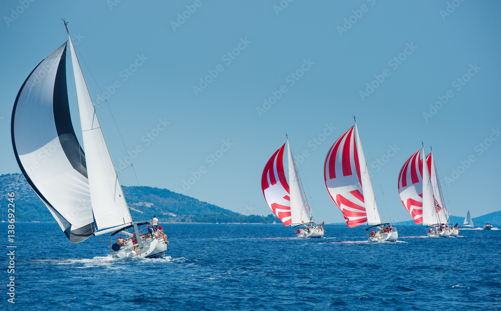 Fototapeta premium Sailing boat with black and white spinnaker catching up sailing boat on horizon