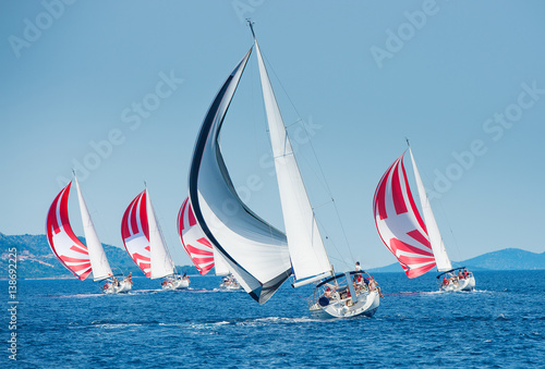 Sailing boat with black and white spinnaker catching up sailing boat on horizon