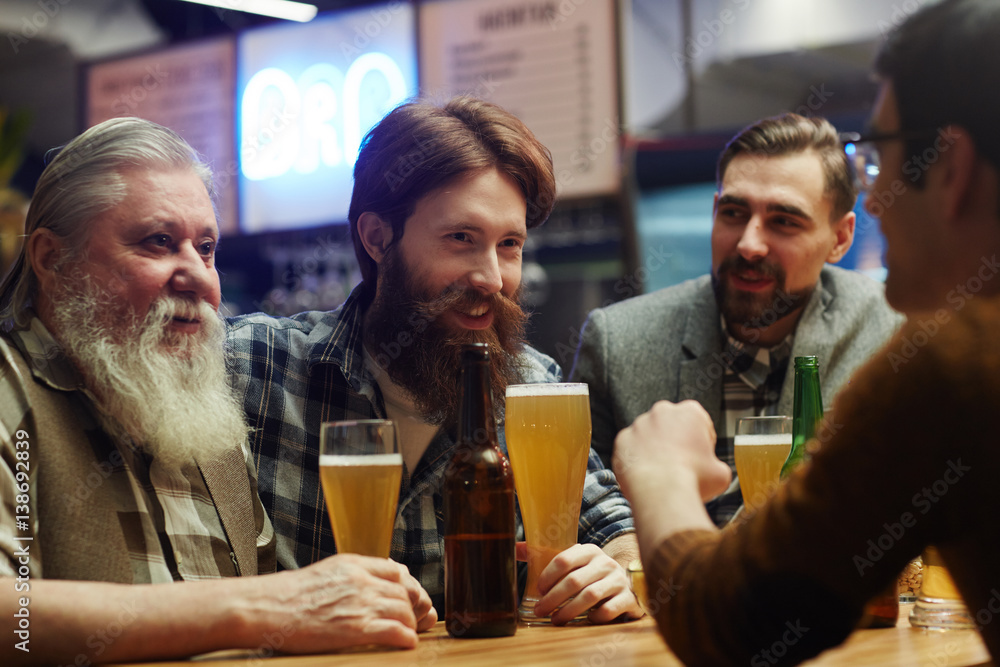 Happy men with beer spending traditional Irish holiday in pub