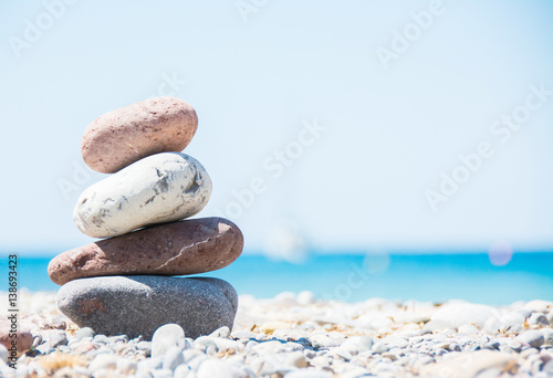 Relaxing in summer concept. Stones on the beach with boat on background.