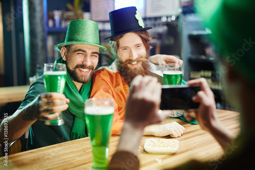 Happy guys with beer having been photographed by their friend in pub