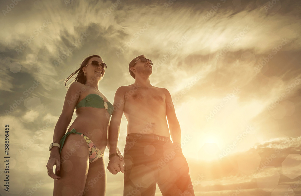 Fototapeta premium Couple stay on the beach under sky with sunlight.