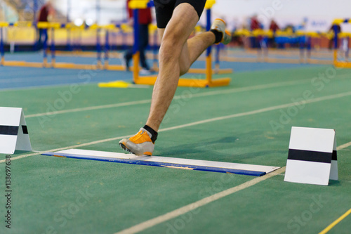 Sportsman landing his leg on fault line of board before taking off in long jump or tripple jump competition photo