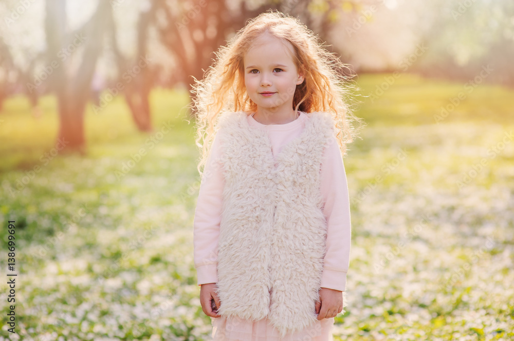 spring portrait of beautiful child girl with curly long hair walking outdoor in blooming garden spring portrait of beautiful child girl with curly long hair walking outdoor in blooming garden
