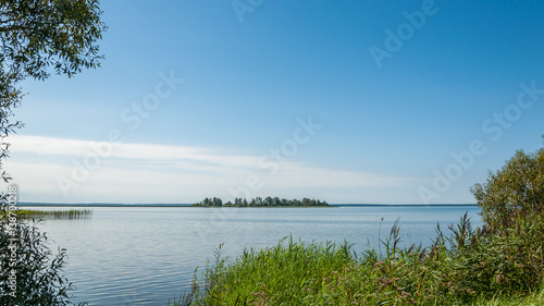 big beautiful lake bright summer day. view from the shore of the bushes and grass