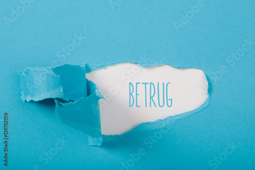 Betrug (fraud in German) message on paper torn ripped opening