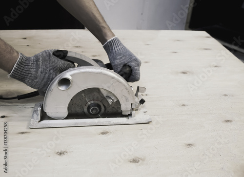 Hands in gloves hold working circular saw