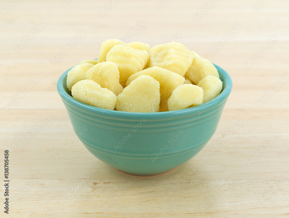 Plain potato gnocchi in a green bowl atop a wood table. Plain potato gnocchi in a green bowl atop a wood table.