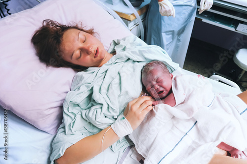 Canvas Print Mother holding her newborn baby after labor in a hospital.