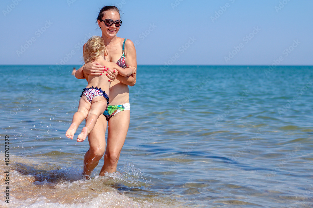 Little baby girl with mother on beach