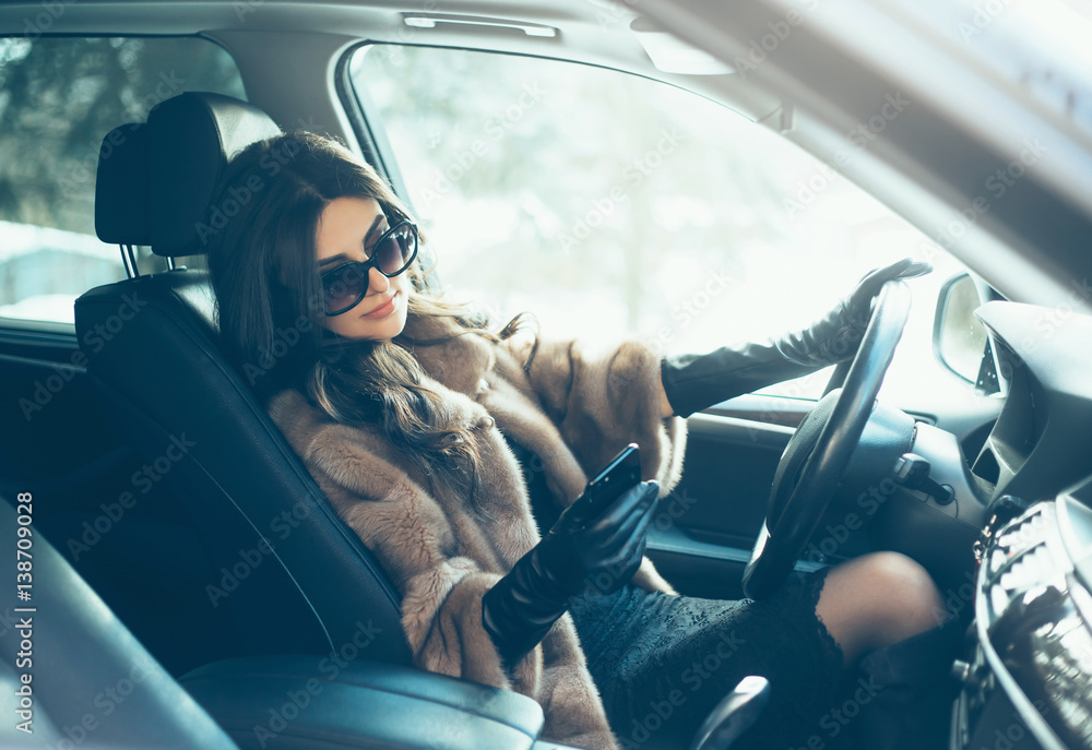 Young beautiful brunette inside the car with wheel in hands