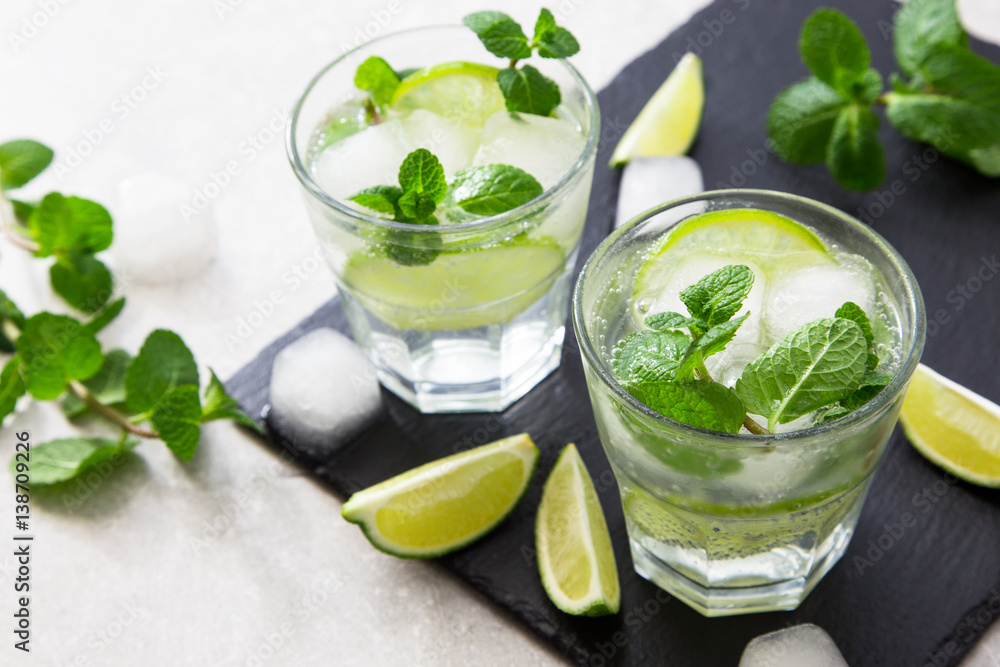 Cold refreshing summer lemonade mojito in a glass on a slate board and stone background. Cold refreshing summer lemonade mojito in a glass on a slate board and stone background.