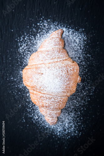 Fresh croissant on a black slate background. Top view