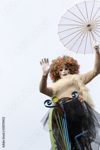 MILAN - FEBRUARY 26: woman on bicycle and paper umbrella poses for photographers disguised with wig and mask during carnival party, Milan on february, 2017 in Italy